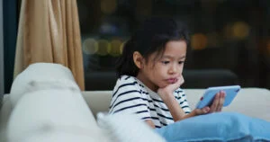 Asian girl watch on mobile phone at home in the evening