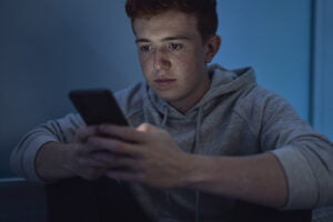 Teenage boy using mobile phone while sitting at night in his room