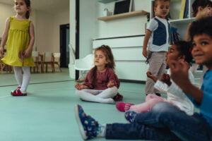 Cheerful children sitting on the floor and having fun at kindergarten