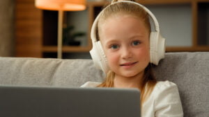 Young girl in headphones sit at looking at a laptop