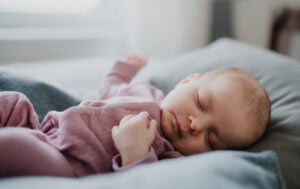 a portrait of newborn baby girl, sleeping on bed