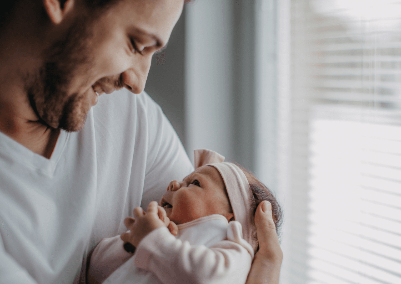 Newborn baby with dad smiling as he things about essential shopping list