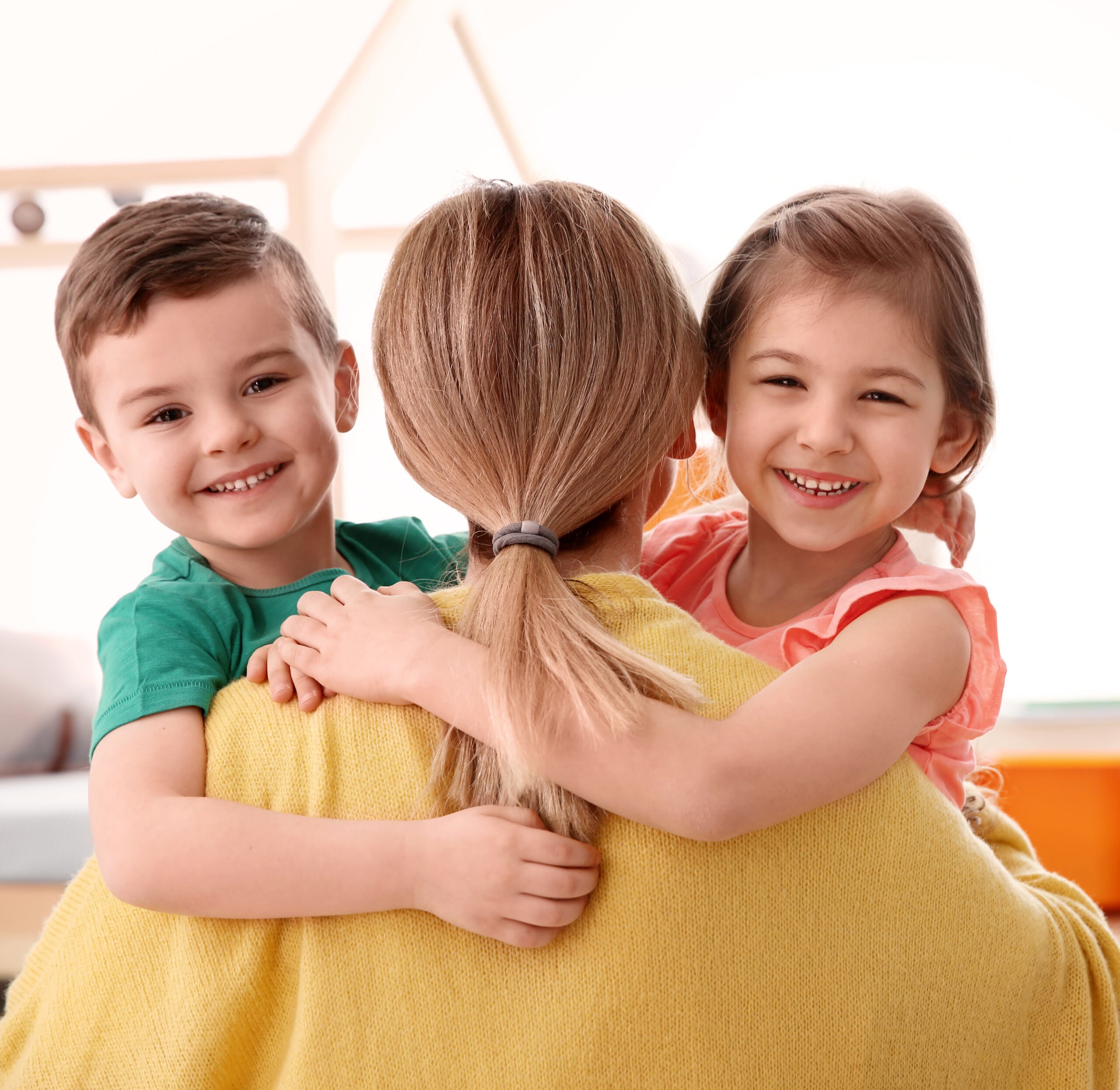 childminder holding a young boy and girl smiling