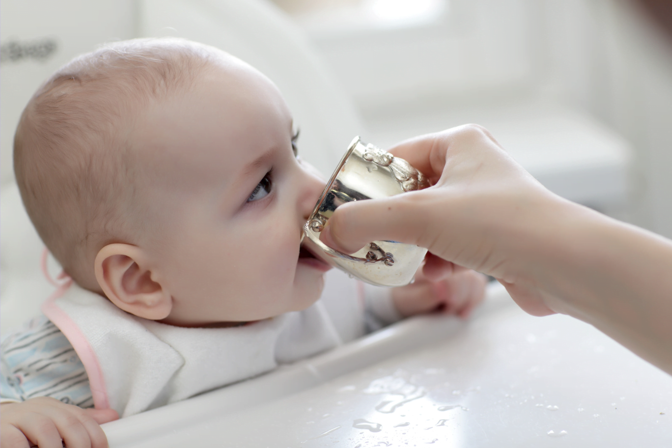 Baby drinking cooled boiled water for constipation in free flow cup