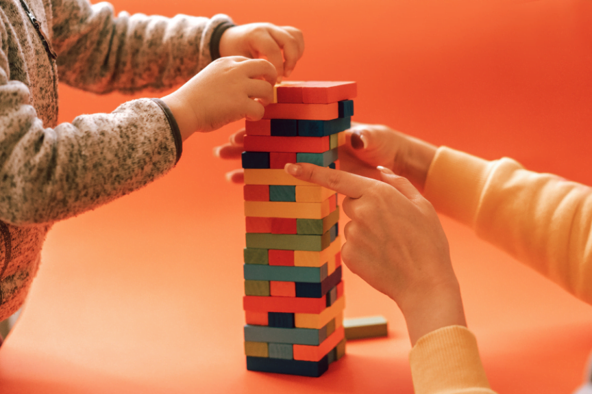 child and mother have fun playing cooperative games like jenga