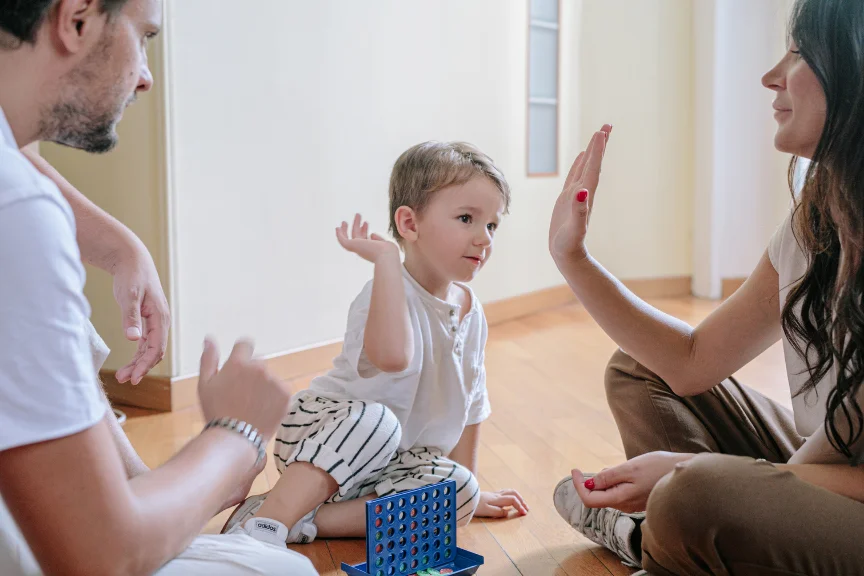 Parents with board hame encouraging child after win