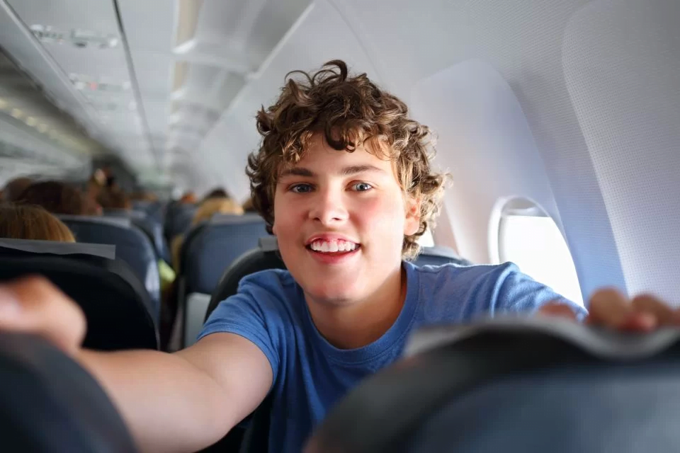 Boy on plane flying alone happy and relaxed