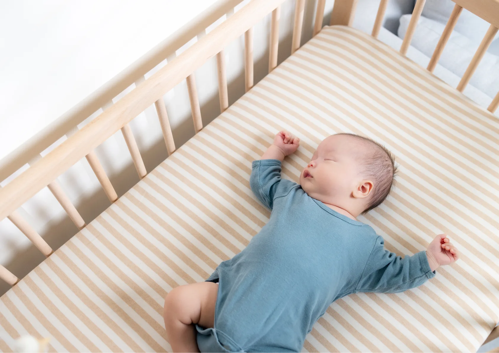 baby underneath no blanket sleeping safely in cot