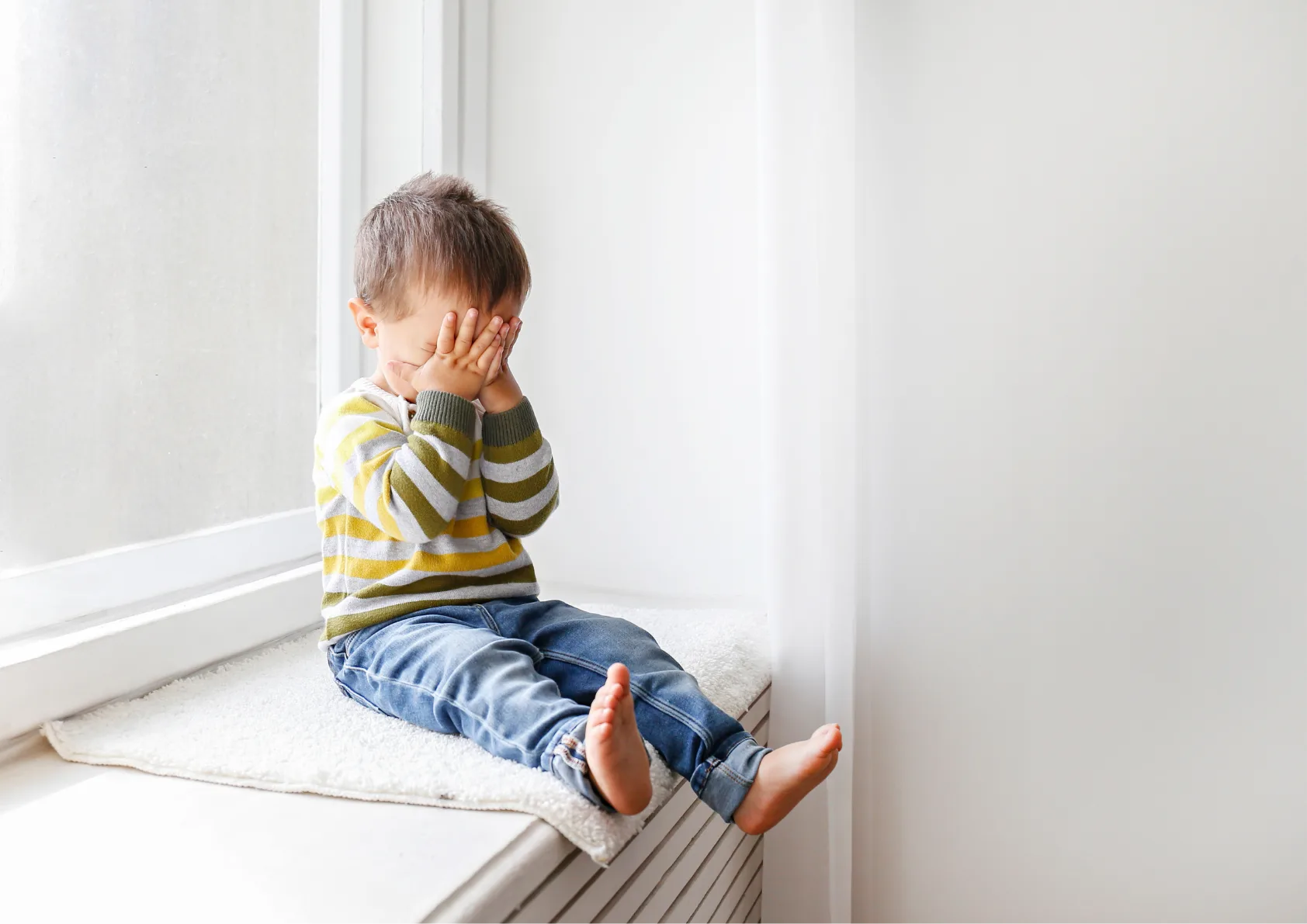 Toddler with working parents looking into hands by window