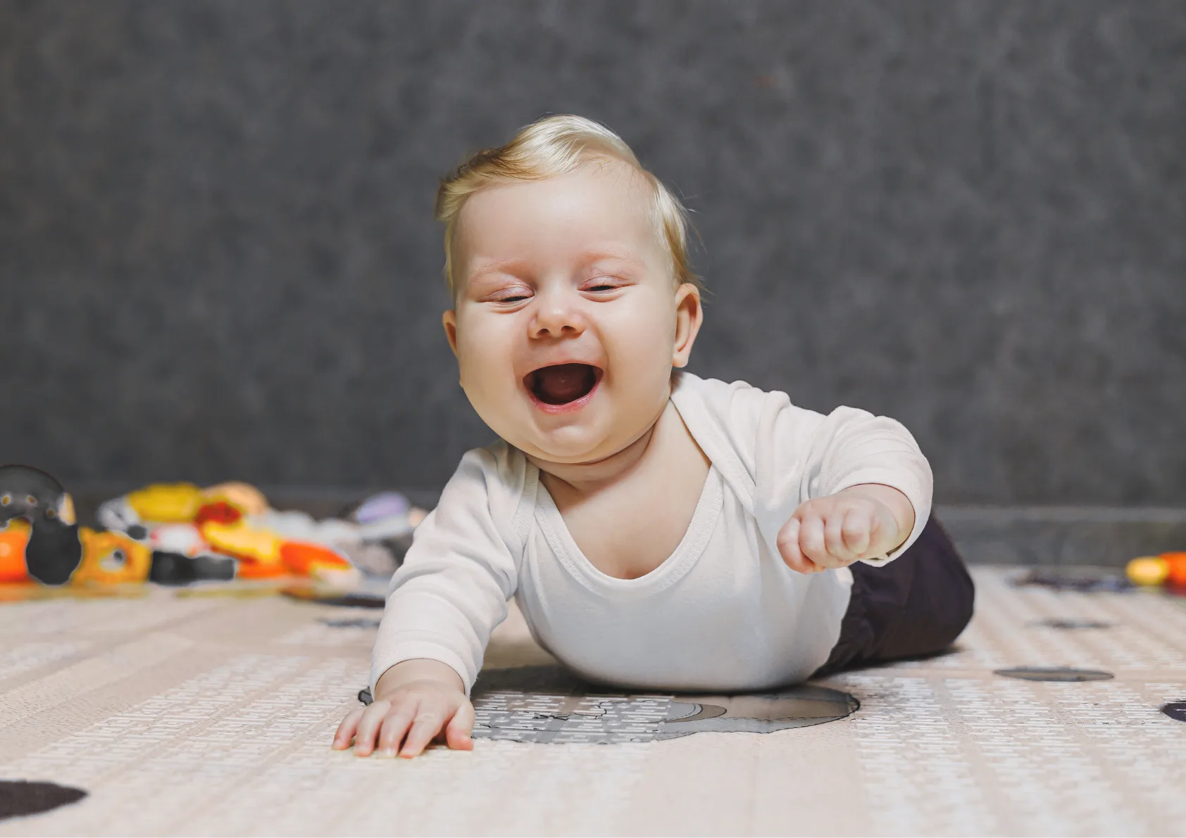 5-month-old boy smiling with normal development milestones lifting head and chest off playmat