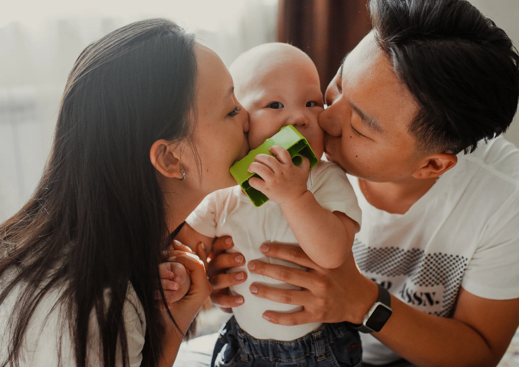 Parents kissing baby on cheeks