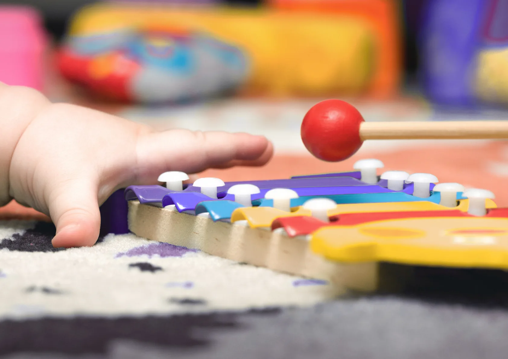 Infant hand holding colourful musical toy